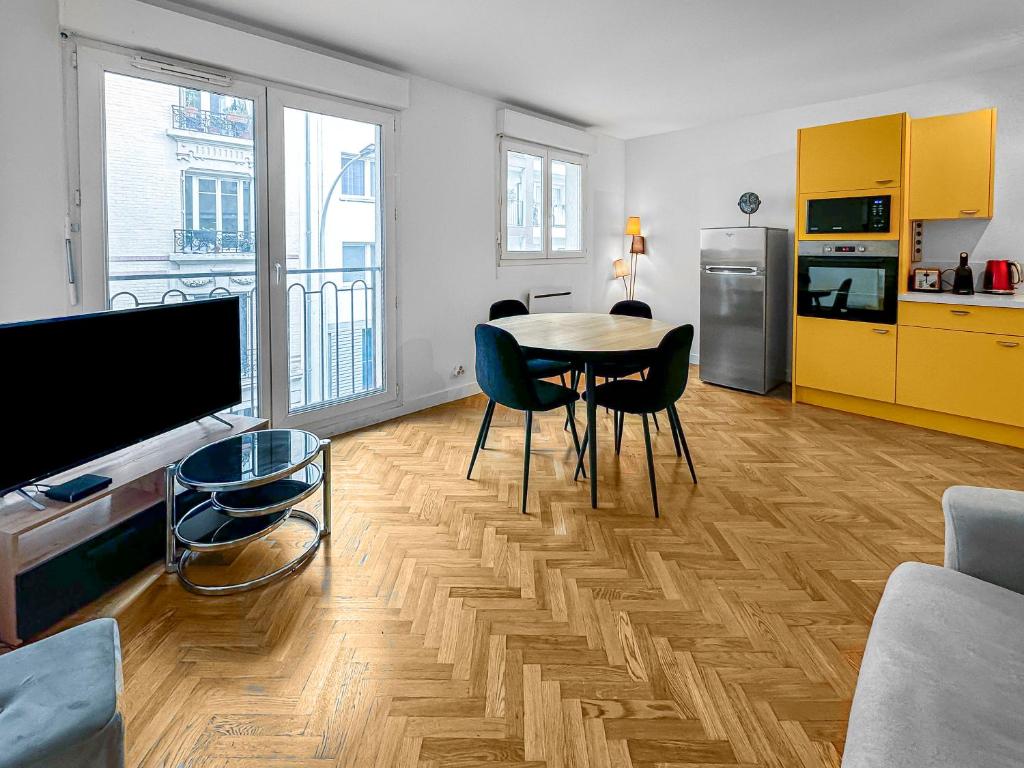 un salon avec une table et des chaises et une cuisine dans l'établissement Style et Tranquillité au Kremlin-Bicêtre, au Kremlin-Bicêtre