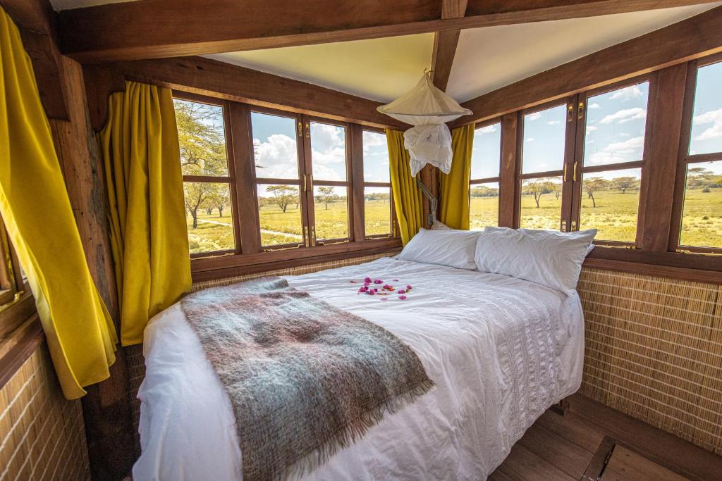 een slaapkamer met een bed in een kamer met ramen bij The Watch Tower 360' Bed View Shower Understars in Naivasha