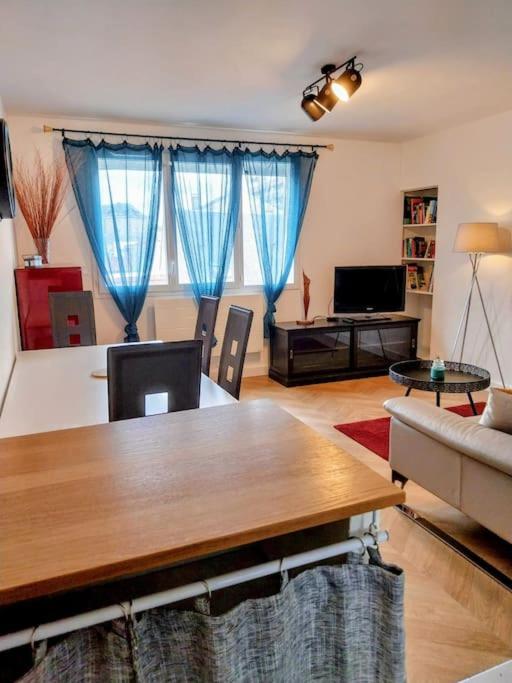 - un salon avec une table et des rideaux bleus dans l'établissement Le Saint Jean - 2 chambres - centre ville, à Tarbes