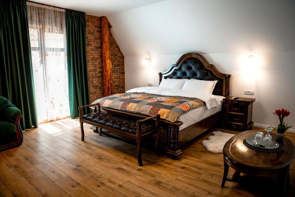 a bedroom with a bed with a bench and a table at Boutique Marlen in Ghimbav