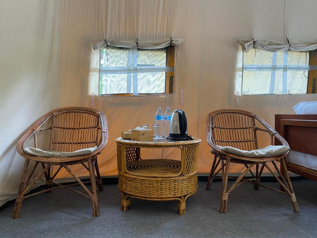 a room with two chairs and a table with a microwave at Hotel Tharu Garden And Beer Bar in Chitwan