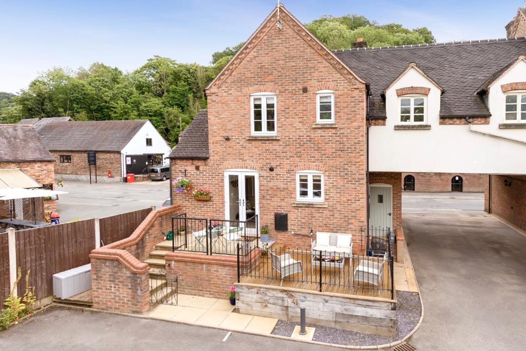 a brick house with a balcony with tables and chairs at Salthouse Cottage in Ironbridge in Telford