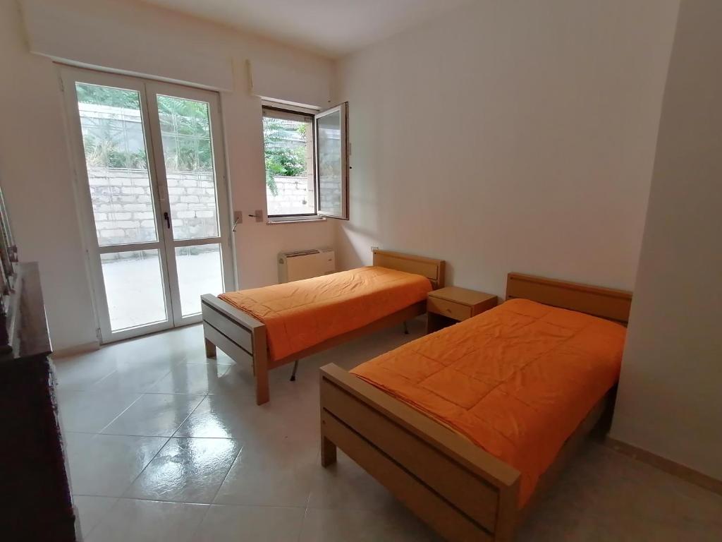 a bedroom with two beds and a window at Appartamento 3 letti con cucina e parcheggio privato gratuito in Candela