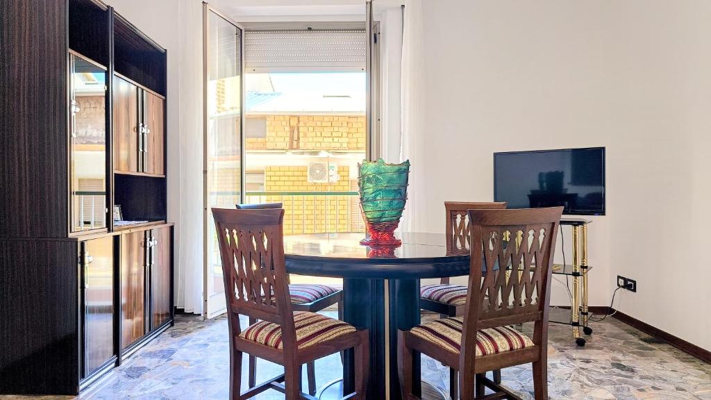 a dining room table with chairs and a vase on it at MaisonV-Vivi il centro e il mare in Porto San Giorgio