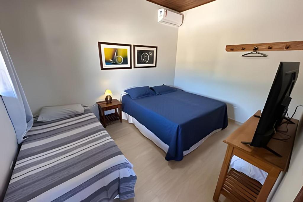 a bedroom with a bed and a flat screen tv at Linda Casa C/ Vista pro Mar na Praia Grande em Paraty in Paraty