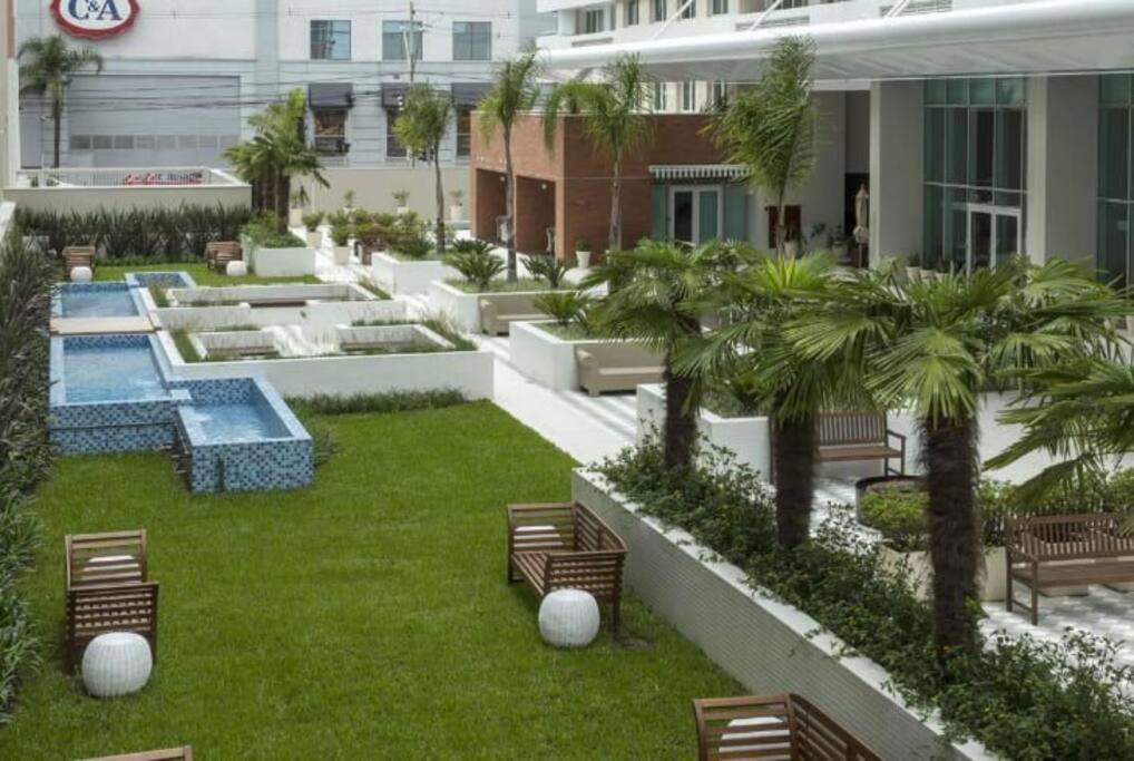 a resort yard with benches and a pool and palm trees at Espaço especial IX in Curitiba
