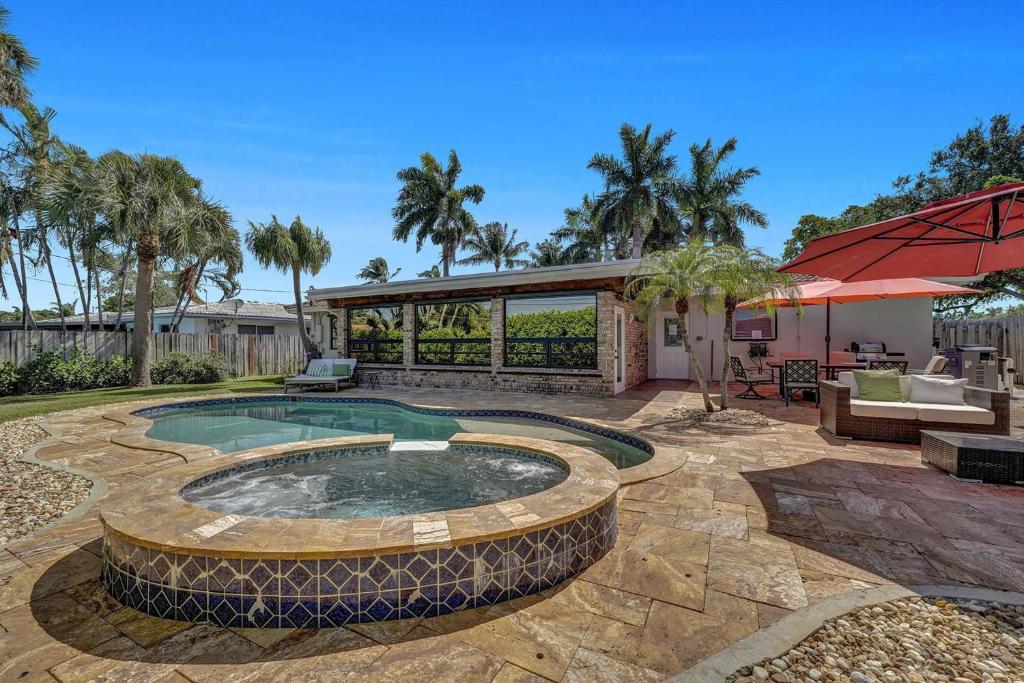 a backyard with a swimming pool and a house at Alfresco Beach Getaway in Pompano Beach