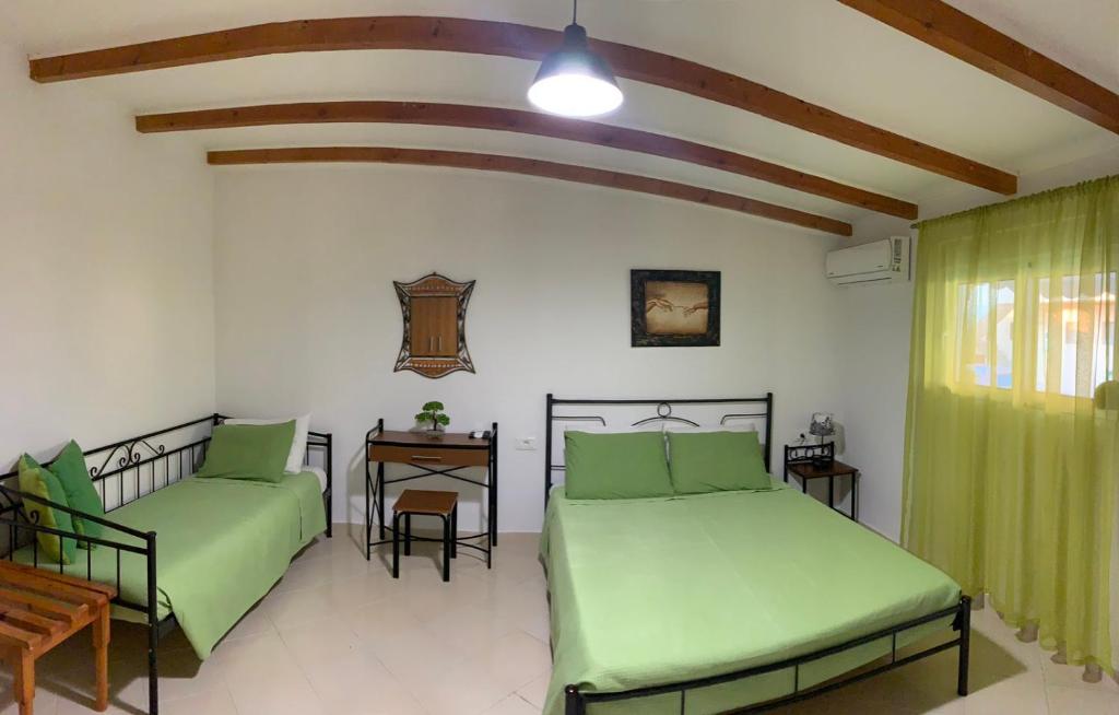 two beds in a room with green sheets and a table at SERENITY House in Faliraki