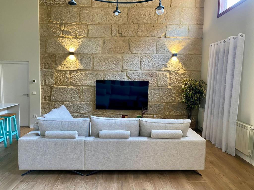 ein Wohnzimmer mit einer weißen Couch vor einer Steinwand in der Unterkunft Villa Maca in Pontevedra