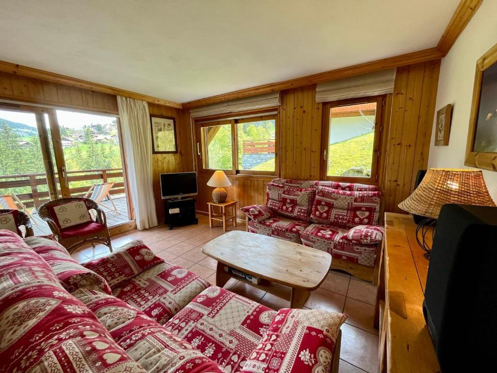 - un salon avec des canapés, une table et des fenêtres dans l'établissement Appartement ski aux pieds, 2 chambres, terrasse et parking couvert - La Clusaz - FR-1-459-49, à La Clusaz