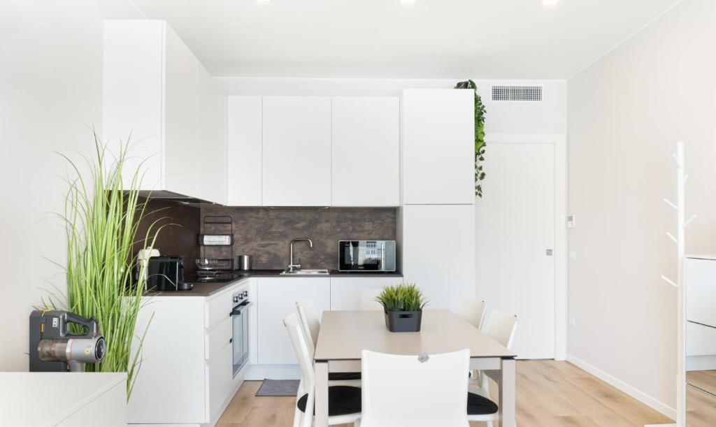 a kitchen with white cabinets and a table and chairs at Casa Eolo Mare e Relax in Lido di Jesolo