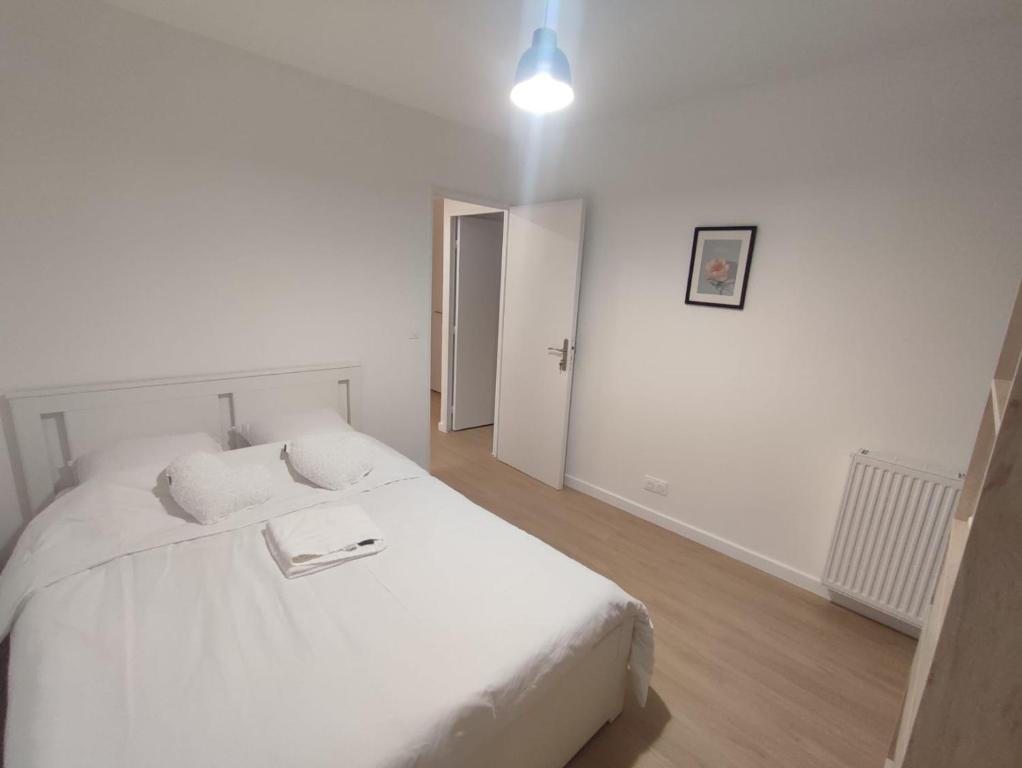 - une chambre blanche avec un lit blanc et un couloir dans l'établissement Apparemment familial, Évry-Courcouronnes