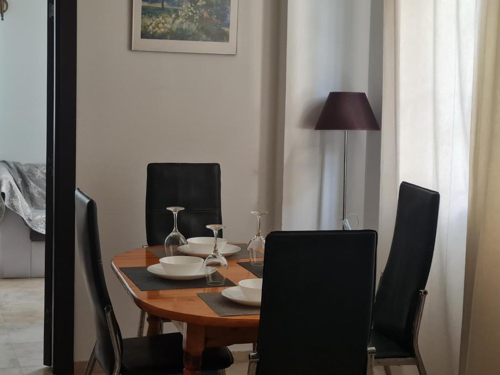 ein Esstisch mit schwarzen Stühlen und ein Tisch mit Tellern und Weingläsern in der Unterkunft Apartment Almi - The Cliff Obzor in Obsor