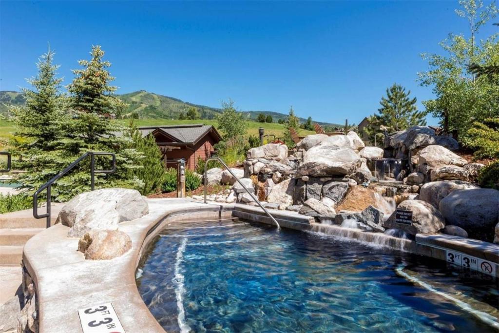 a pool with a waterfall and rocks in a yard at Game Room, Heated Pool, Hot Tubs, Private Washer Dryer in Steamboat Springs