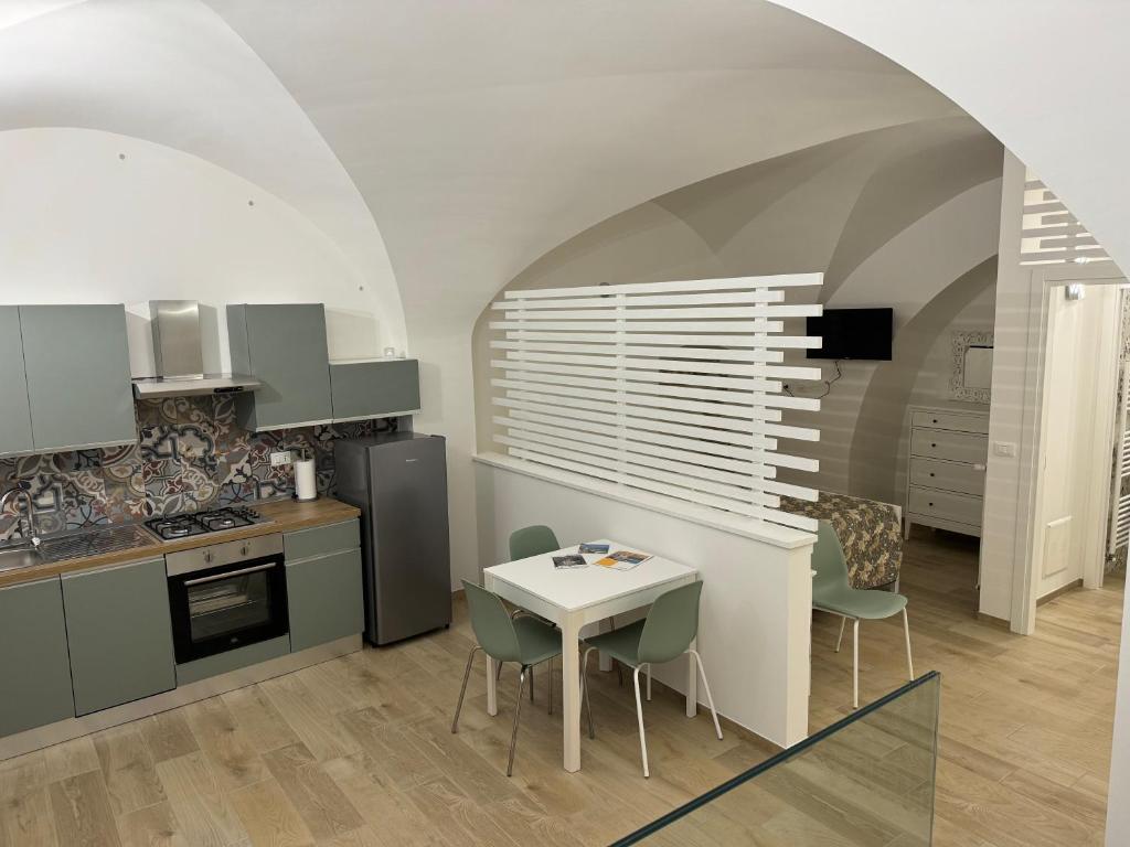 オルトーナにあるCasetta La Ritornaの緑のキャビネットとテーブルと椅子のあるキッチン