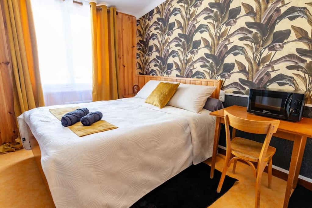 Un dormitorio con una cama con un escritorio y un televisor. en La Rosée - Studio Bali - Wifi, Smart TV, en Bourbonne-les-Bains