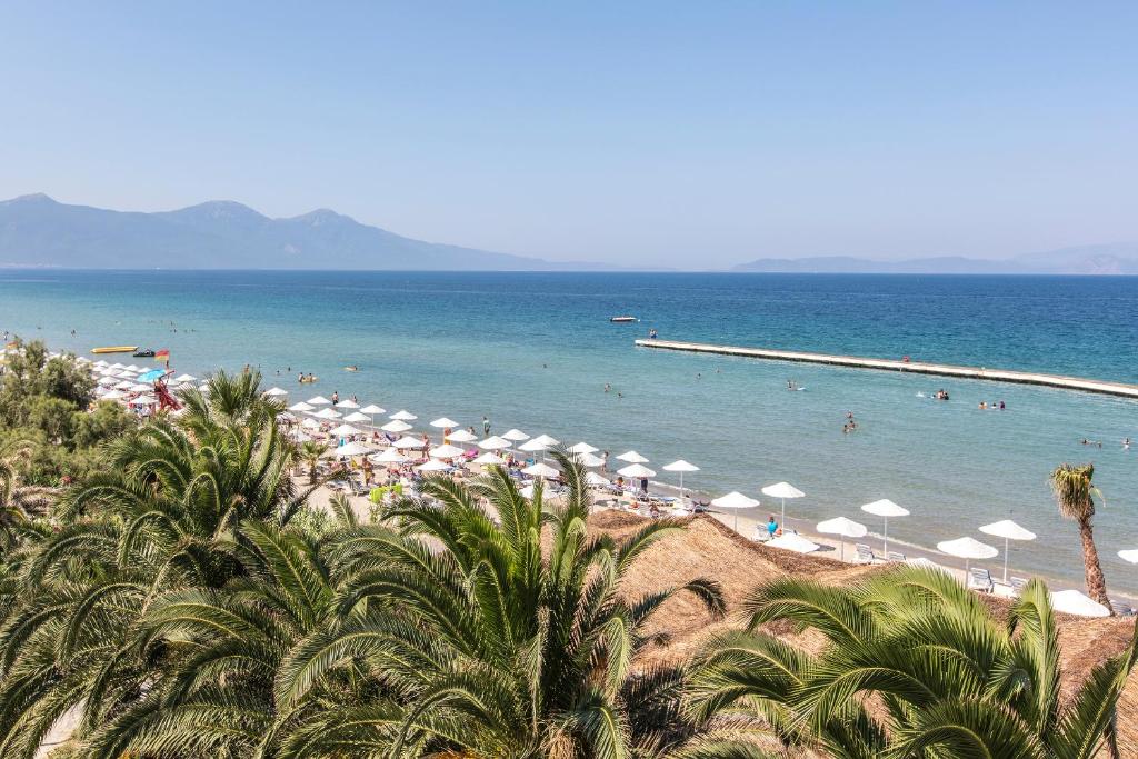 ein Strand mit Sonnenschirmen und Menschen im Wasser in der Unterkunft Atlantique Holiday Club - All Inclusive in Kusadası