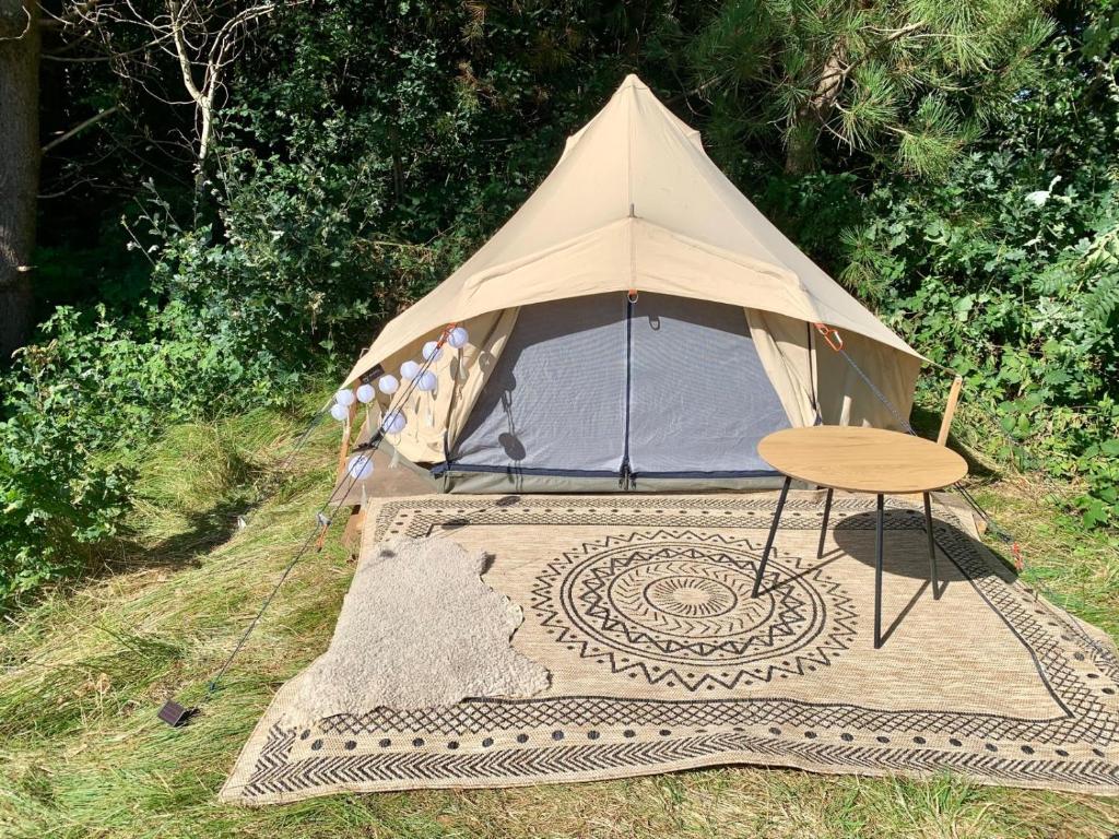 a tent with a table and a chair on a rug at Bell tent Boven Duin in 't Horntje