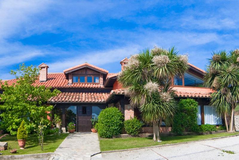 une maison avec des palmiers devant elle dans l'établissement La Posada de Langre Anexo, à Langre