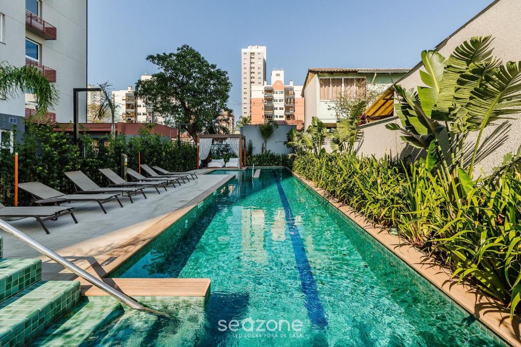 a swimming pool with chaise lounge chairs next to a building at Studio Completo ao Lado da PUCRS CON1506 in Porto Alegre