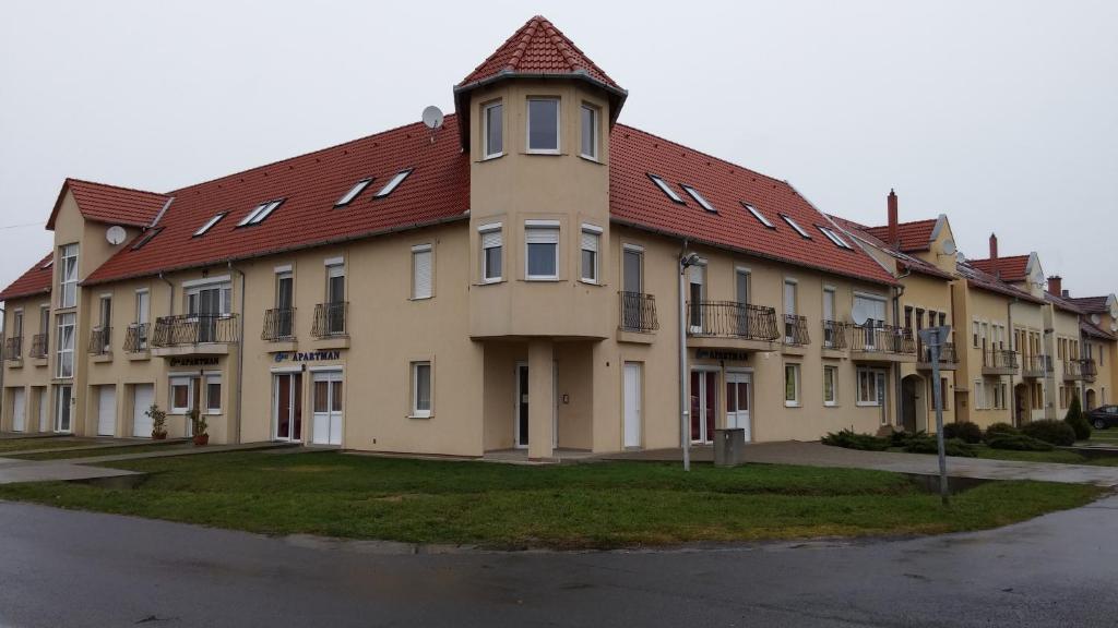 ein großes, braunes Gebäude mit rotem Dach in der Unterkunft Éva Apartman in Szigetvár