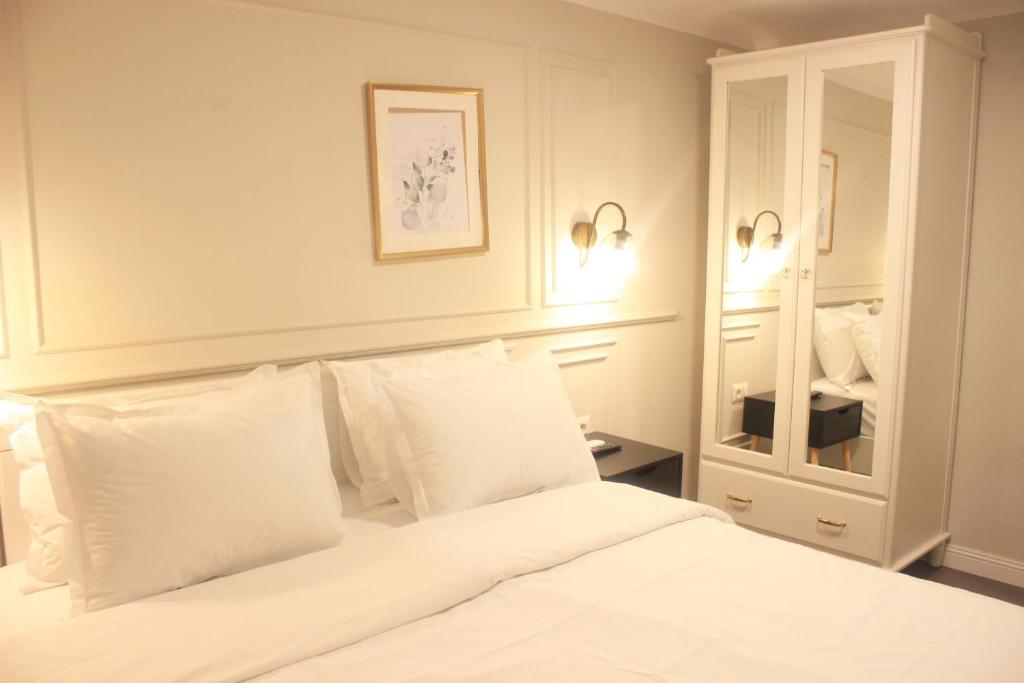 een slaapkamer met een wit bed met witte kussens bij Lev Or Aparthotel in Boekarest