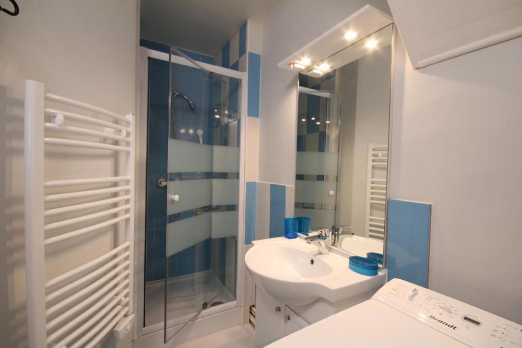 une salle de bain blanche avec un lavabo et une douche dans l'établissement Studio face au lac, à Bagnoles-de-l'Orne
