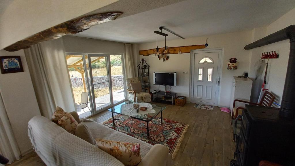 a living room with a couch and a tv at Assos Egedebirnefes Kır Evi in Ayvacık