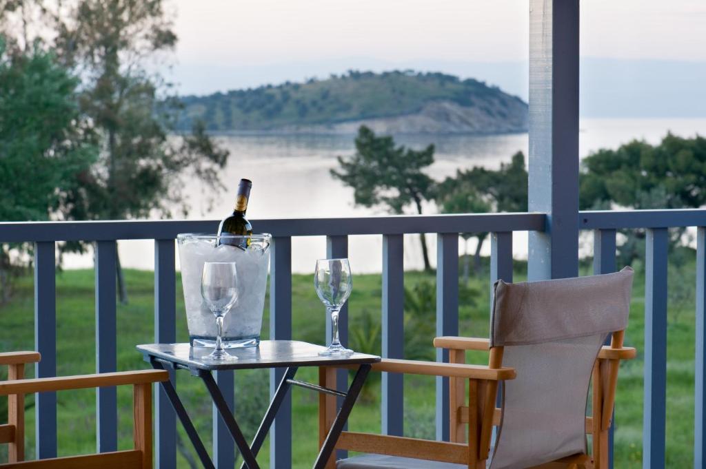 a bottle of wine and two glasses on a table on a balcony at Serenity Estate in Ormos Panagias