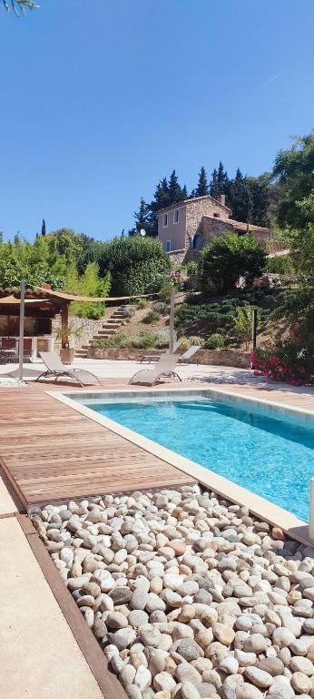 - une piscine avec des rochers à côté d'une maison dans l'établissement Cyprès du château, à Le Barroux