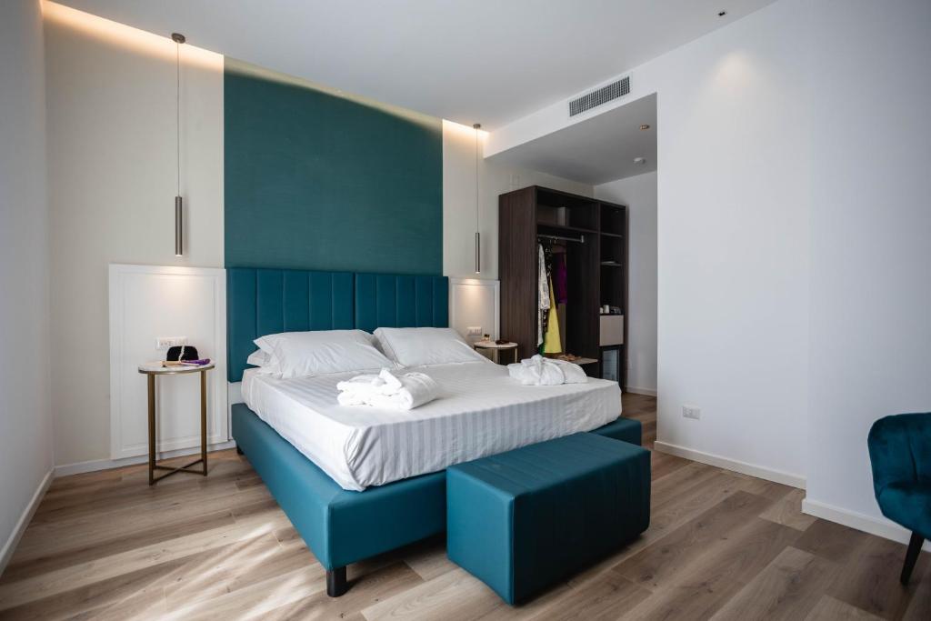 a bedroom with a large bed with a blue headboard at Mondello Glam Hotel & Terrace in Mondello