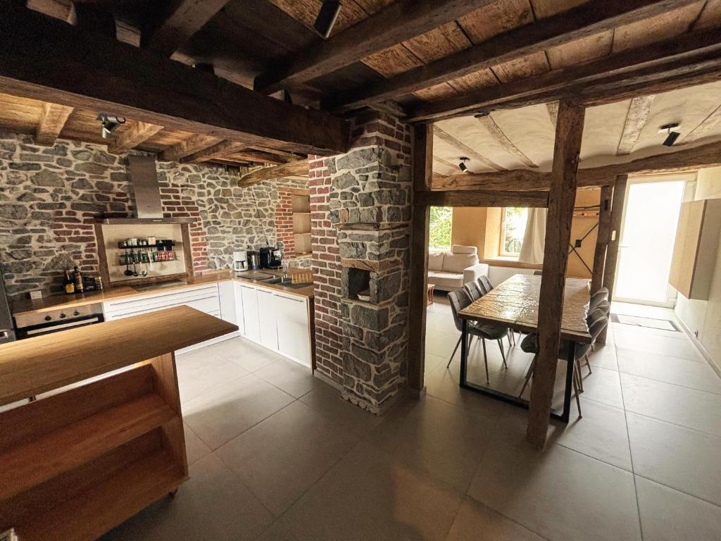 a kitchen with a table and a brick wall at Ancienne ferme totalement rénové moderne à Baelen in Baelen