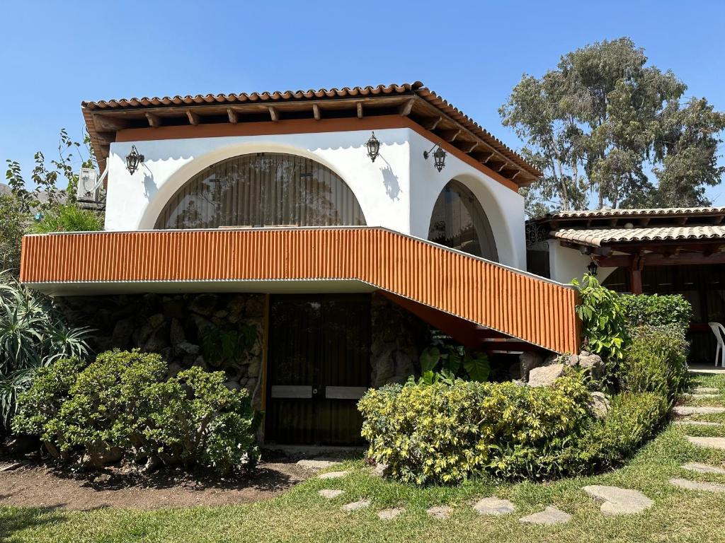 Una casa grande con un fondo naranja y blanco. en Casa de Campo Condominio El Pueblo-Santa Clara,Ate, en Lima
