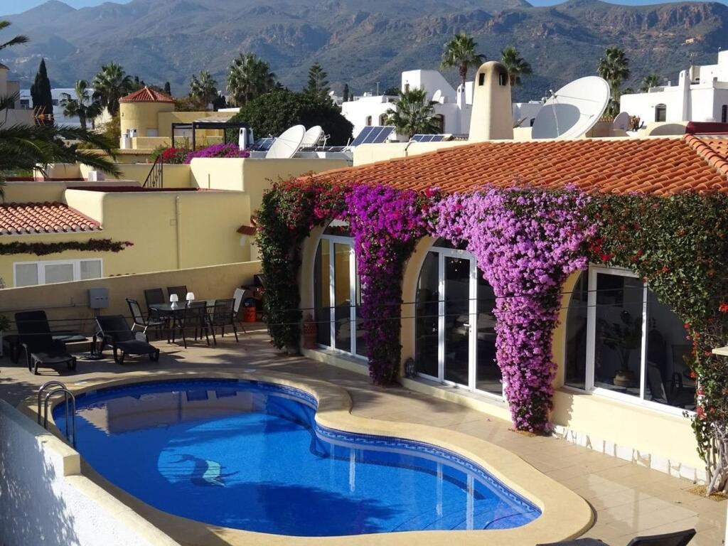 a resort with a swimming pool and purple flowers at Casa Tia, Mojácar with Private Pool and less than 5 minutes from beach! in Mojácar