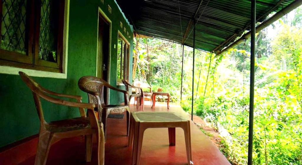 zwei Stühle und ein Tisch in einem Raum mit einem Fenster in der Unterkunft Haniffas Holiday Inn in Kandy