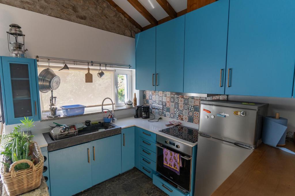 a kitchen with blue cabinets and a stainless steel refrigerator at Cantinho do Bairro Alto in Alijó