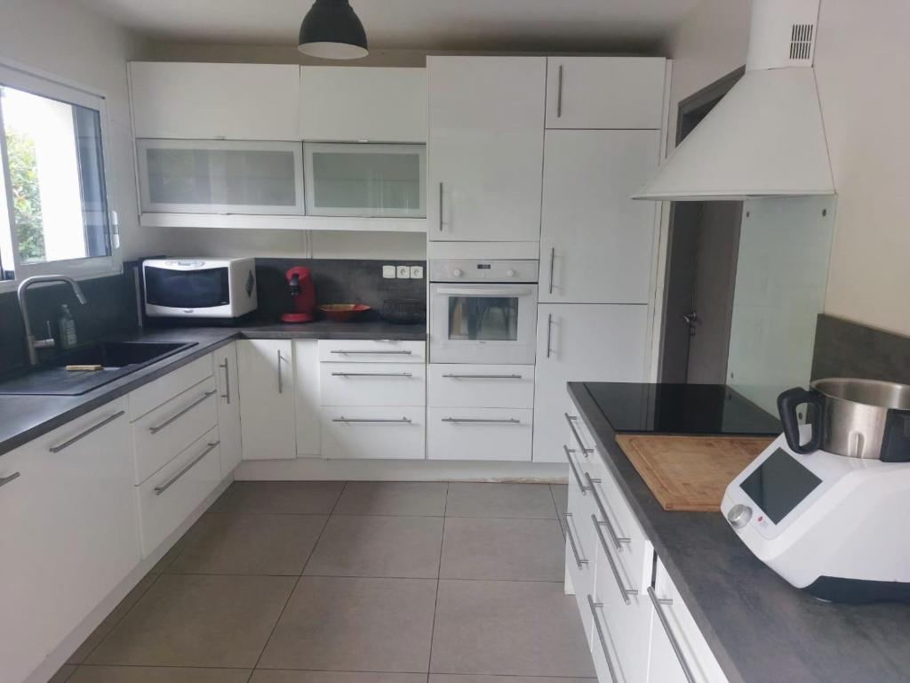 a kitchen with white cabinets and a blender on a counter at Maison de vacances spacieuse et lumineuse, proche Nantes et mer in Treillières