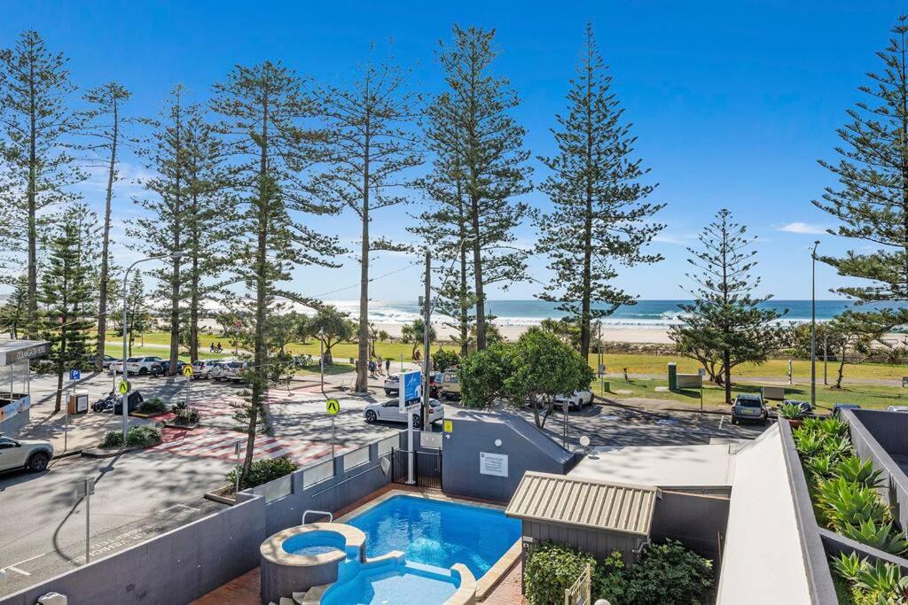 Una vista aérea de una piscina y un estacionamiento con árboles. en Beachfront Beauty - Cooly, en Gold Coast