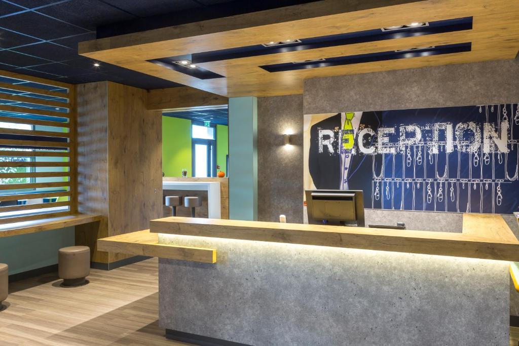 a rendering of a reception desk in a lobby at ibis budget Lorient Hennebont in Hennebont