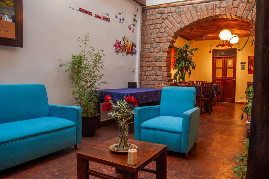 a lobby with two blue chairs and a table at Hotel Casa de las Rosas in Cuenca