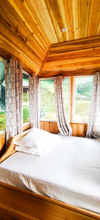 a bed in a wooden room with two windows at Zero Points TheLaure Cottage in Ilām