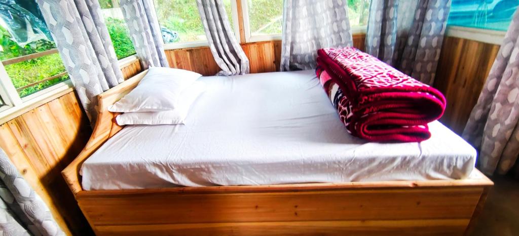 a bed with a red blanket sitting on top of it at Zero Points TheLaure Cottage in Ilām