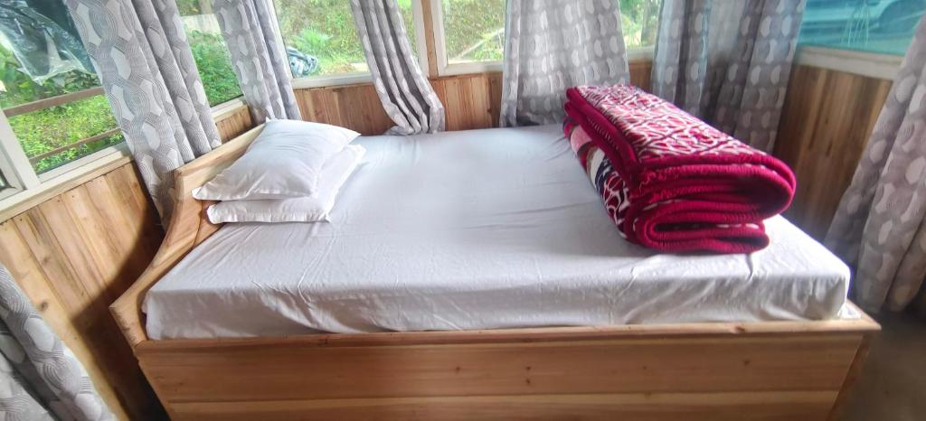 a bed with a red blanket and pillows on it at Zero Points TheLaure Cottage in Ilām