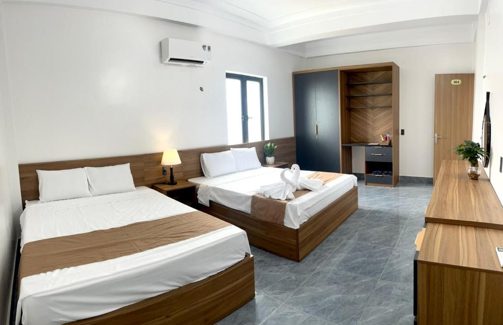 a hotel room with two beds and a desk at Greenhouse in Phong Nha