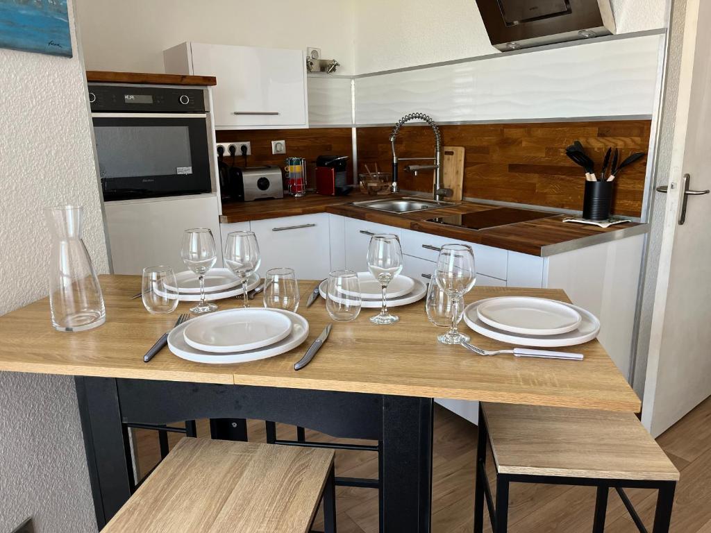 une cuisine avec une table avec des assiettes et des verres à vin dans l'établissement Studio cabine cosy avec parking à Gruissan, 4 pers., proche port et commerces - FR-1-796-80, à Gruissan