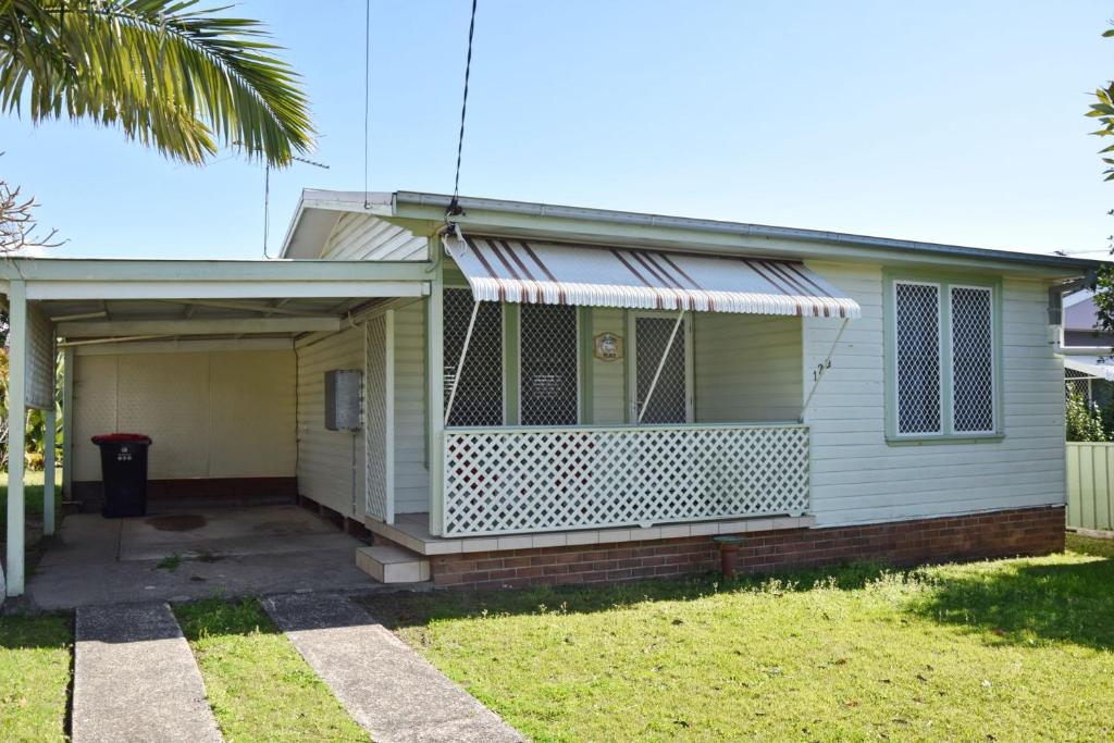 a house with a porch and a garage at Sea Salt Cottage - Bring your own linen. in South West Rocks