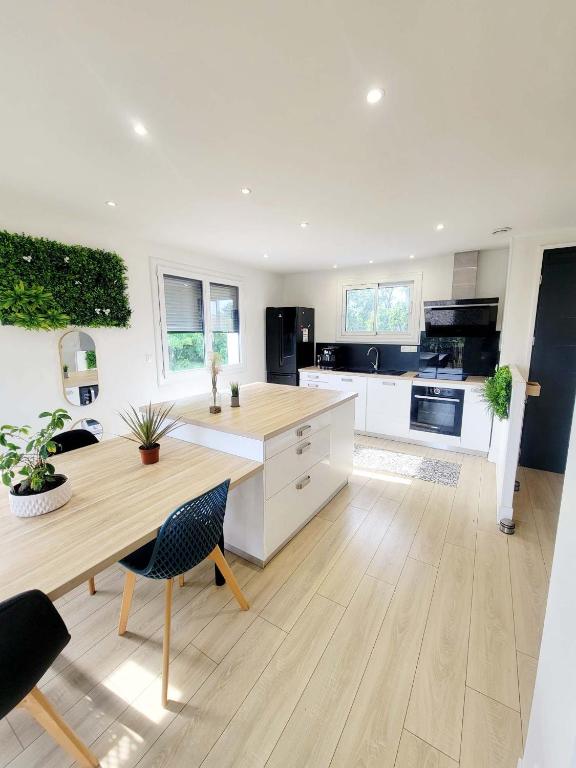 une cuisine avec des armoires blanches et une table en bois dans l'établissement Villa design jacuzzi et clim, à Brens