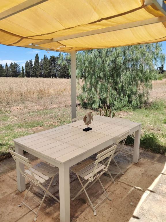 a white table with two chairs under a yellow umbrella at La Fragna in Nardò