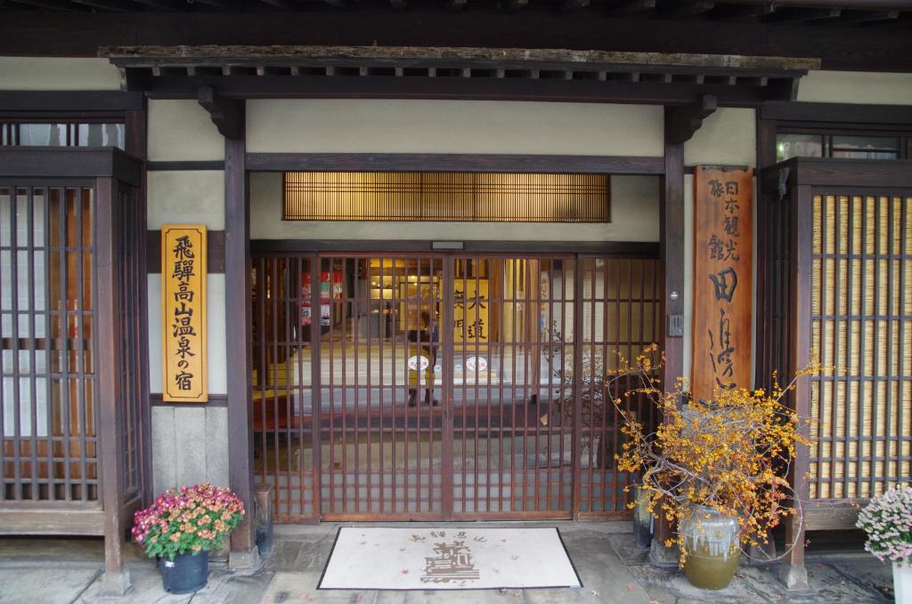 an entrance to a building with a gate and flowers at Ryokan Tanabe in Takayama
