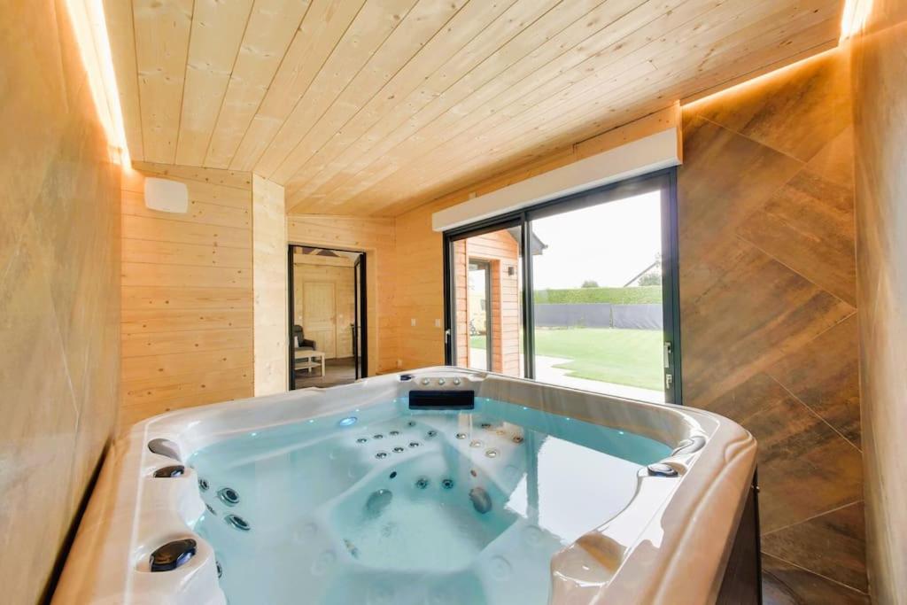 Cette chambre dispose d'une grande baignoire et d'une grande fenêtre. dans l'établissement Le chalet aux portes du pays d Auge, à Saint-Samson